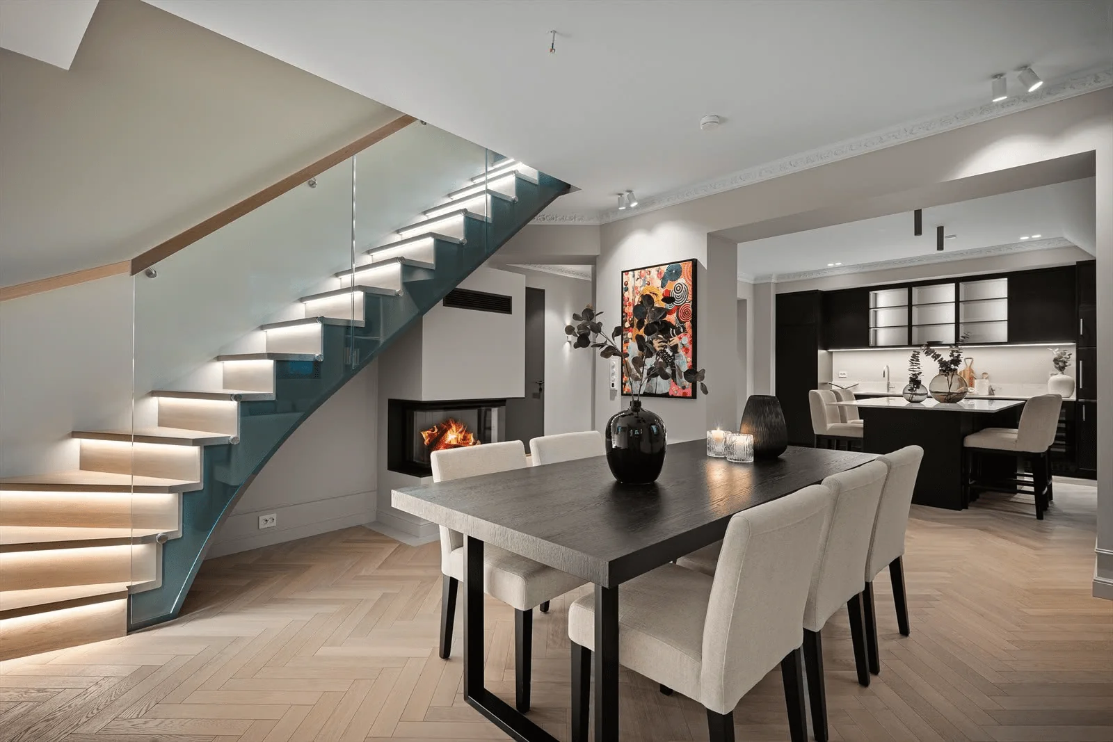 Stue og kjøkken i Carlén House med integrert trappebelysning, downlights og peis